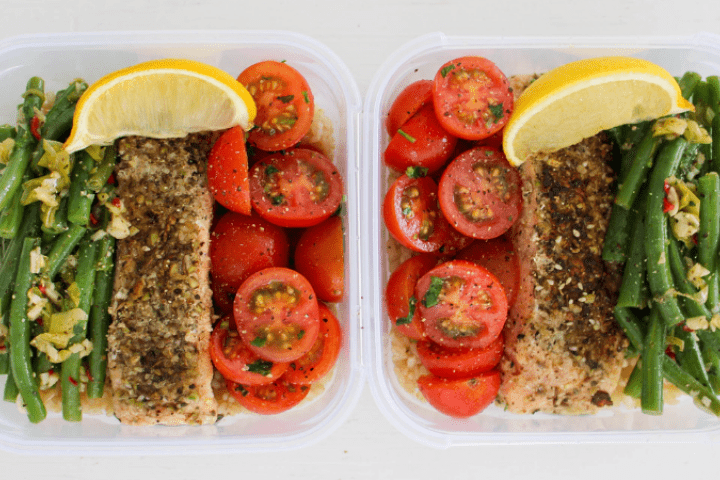 Dukkah salmon served in two containers with beans, tomato and lemon.