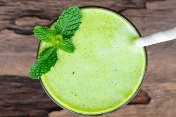 Green smoothie drink in a glass with a straw