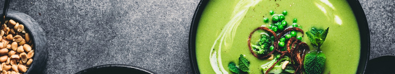 Green peas cream soup in dark plate.
