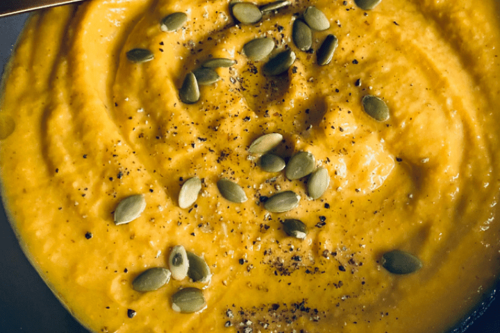 Chickpea pumpkin soup with seeds and pepper on top.
