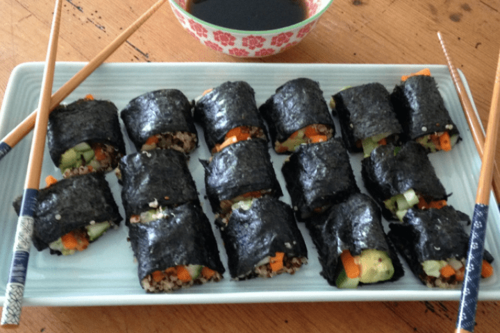 A plate of sushi with chopsticks and soy sauce.