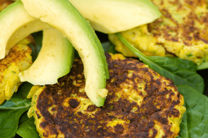 Sweetcorn and zucchini potato cakes with pieces of avocado on top.