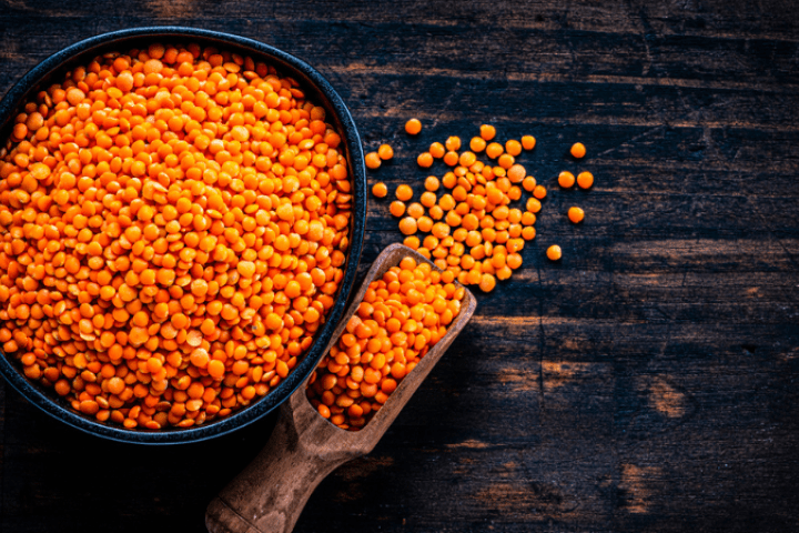 Red lentils in a bowl on a wooden table