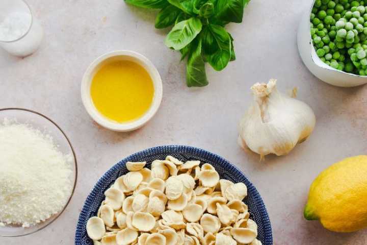 Ingredients for creamy pea pasta on grey backround.