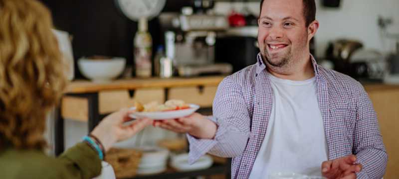 Man with Down syndrome at home having breakfast with woman.