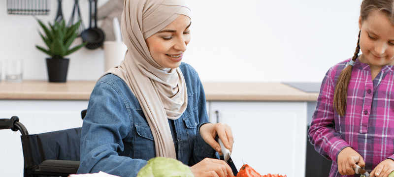 Mother in wheelchair and daughter making salad together