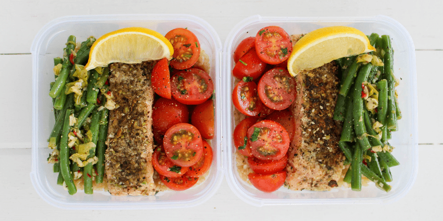 Dukkah salmon served in two containers with beans, tomato and lemon.