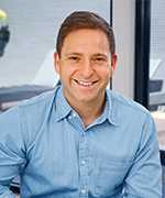 Man with blue shirt and short brown hair smiles at the camera