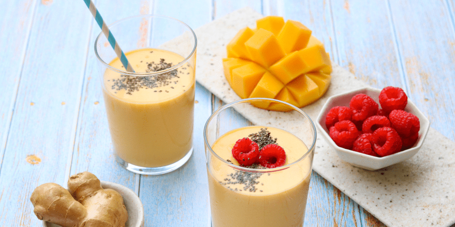 Mango and ginger smoothies with fruit and ginger on the side