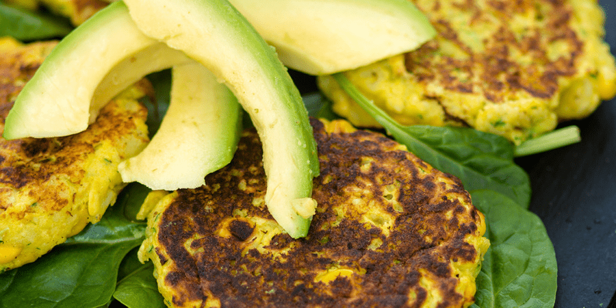 Sweetcorn and zucchini potato cakes with pieces of avocado on top.