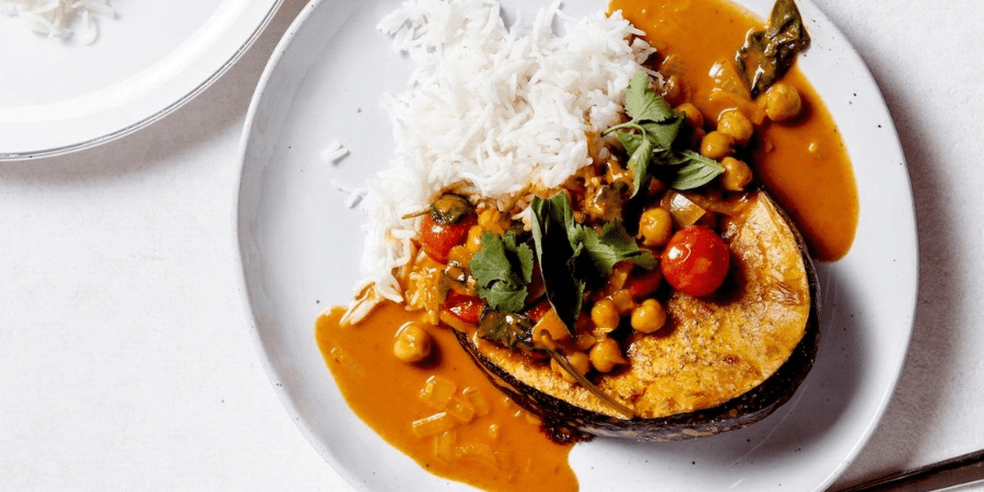 Thai pumpkin and chickpea curry served on a white plate with rice.