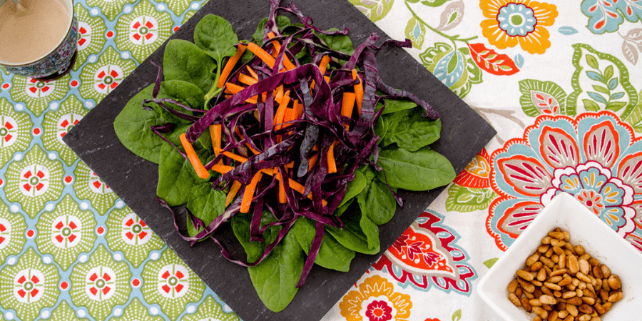 Grated cabbage and carrot on spinach on a black plate