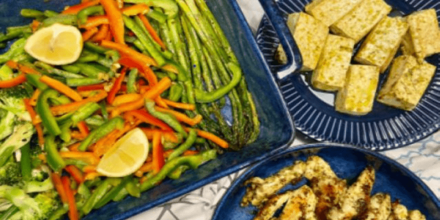 Roasted winter vegetables on a black platter with grilled tofu and chicken