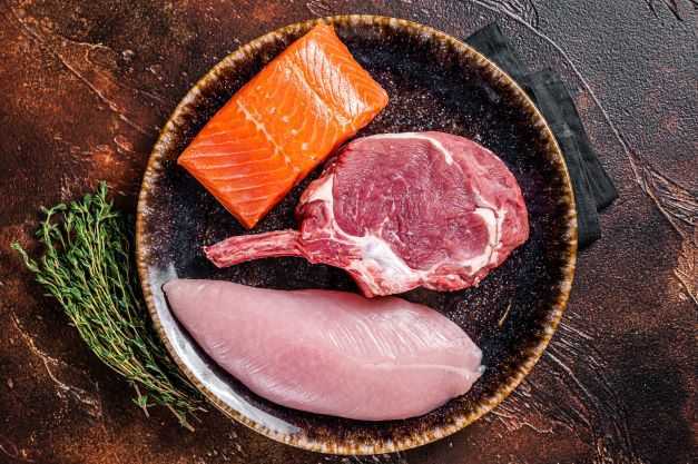 Uncooked raw steaks -fish salmon, beef or veal and turkey breast fillet. Top view.