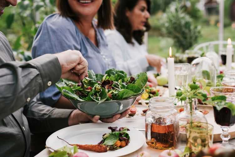 Group of friends sharing a meal at a table outside.