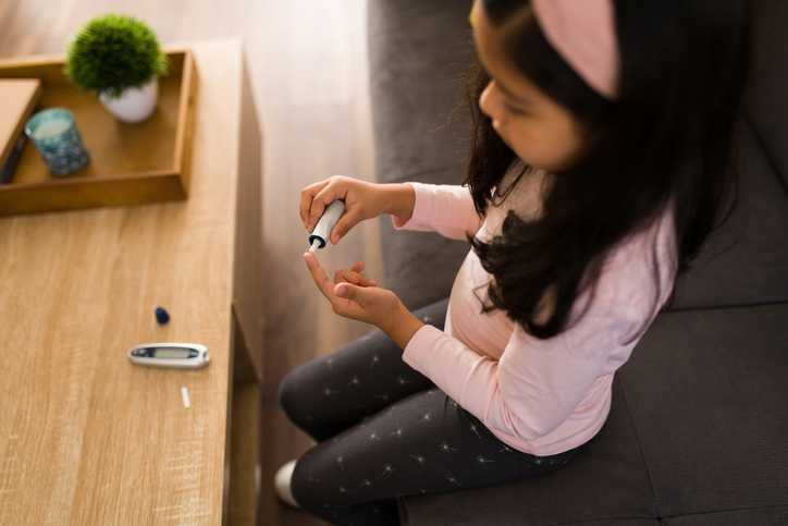 Child with diabetes using a digital monitor to test her blood sugar levels. 
