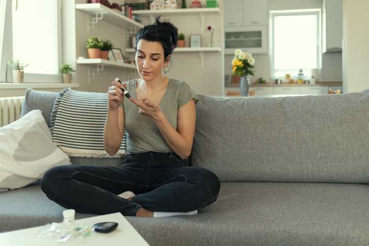 Women checking blood sugar levels by glucose meter at home