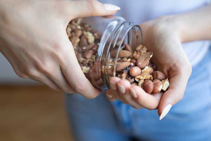 Woman pouring nuts into her hand from a jar
