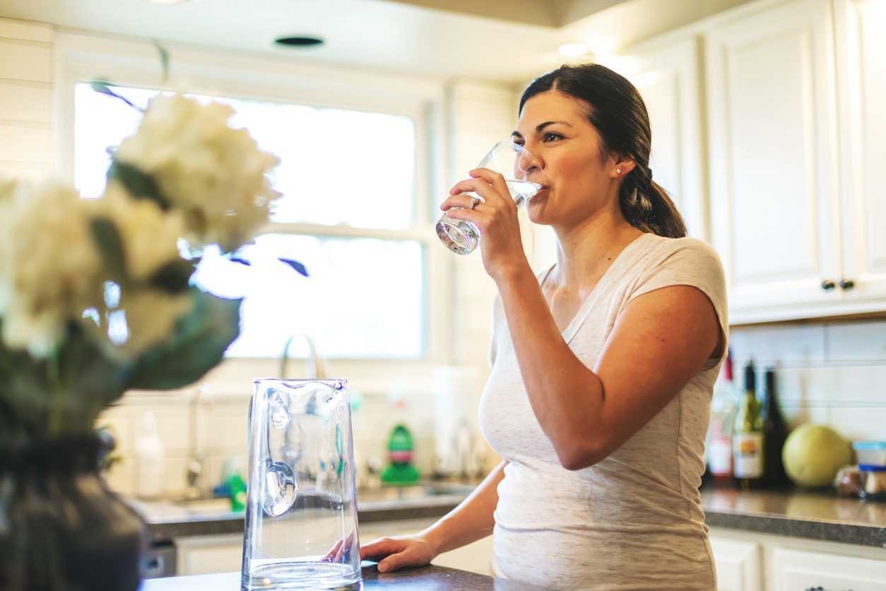 Woman drinking a glass of water in her kitchen