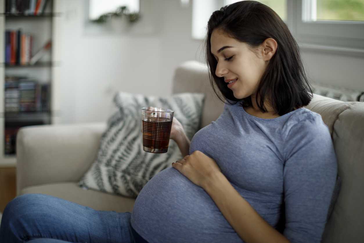 Pregnant woman drinking tea on the couch