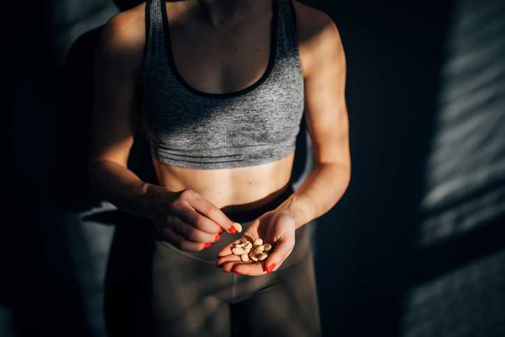 Young woman eating healthy snack after training in the gym.